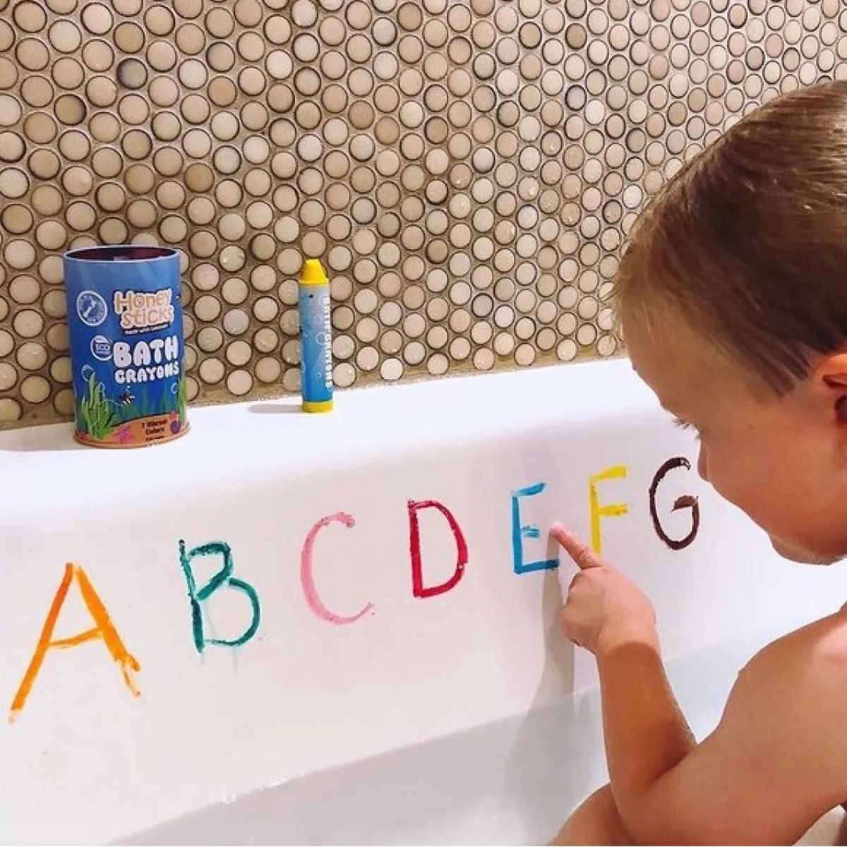 A girl drawing on the bath with the bath crayons