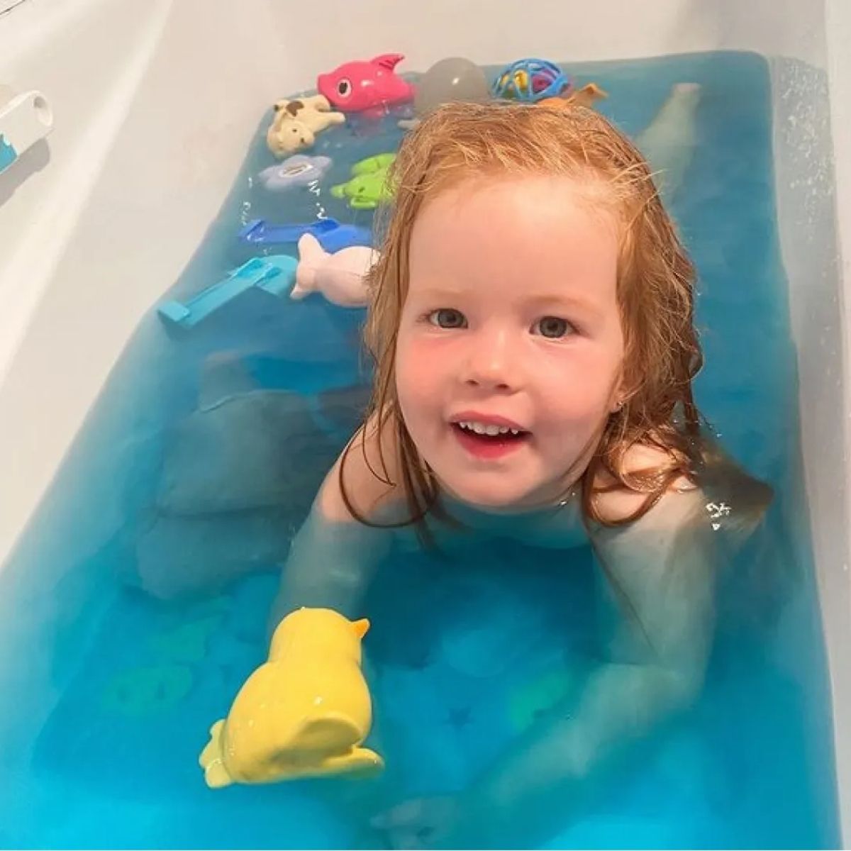 Girl in the bath with the blue bath drops.