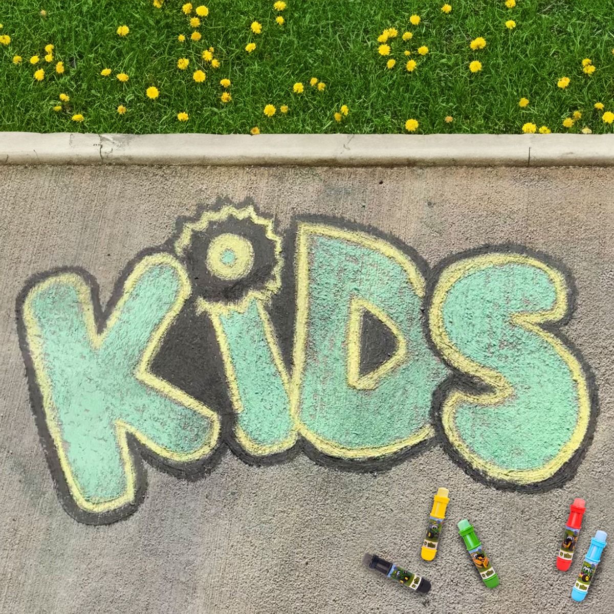 Chalk drawing of &#39;KIDS&#39; on pavement with sidewalk John Deere chalk next to it.